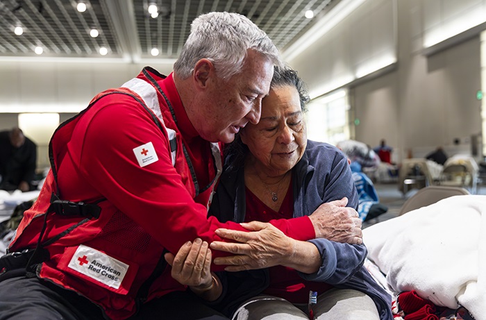 A Red Cross worker provides a comforting embrace to a woman at a Disaster Shelter.